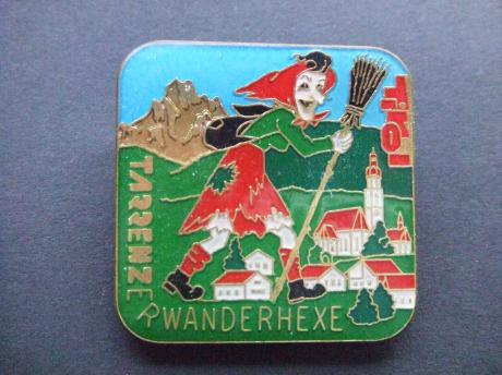 Tirol Heks met bezem wandelend door de bergen